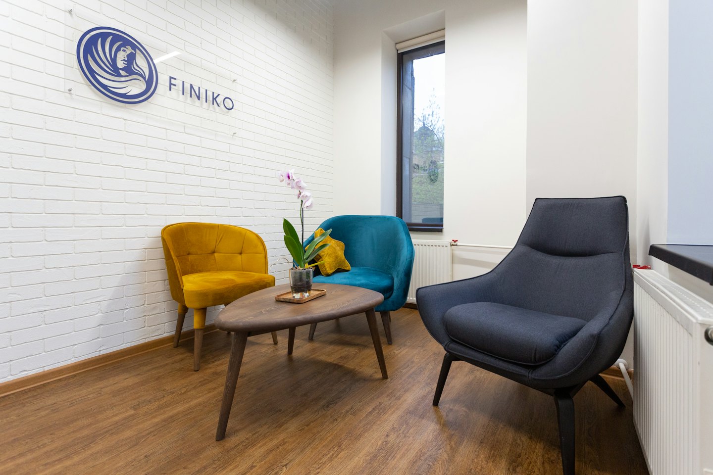 Three colorful armchairs sit around a coffee table in an office lobby.
