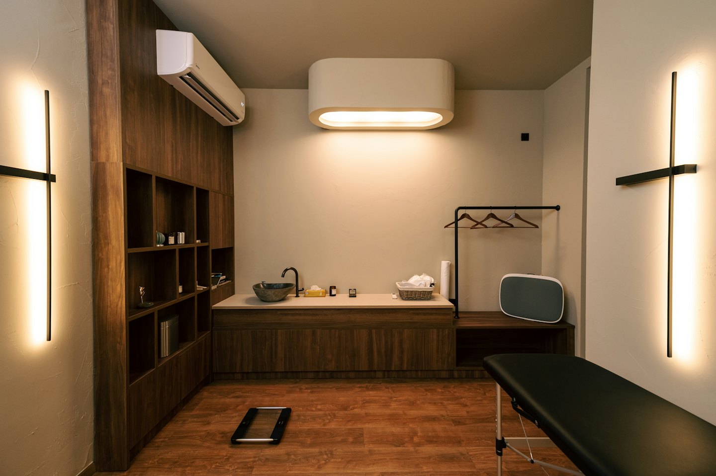 Modern therapy room with black massage table and dark wood cabinets.